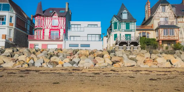 Maisons colorées alignées sur une plage avec des rochers en premier plan
