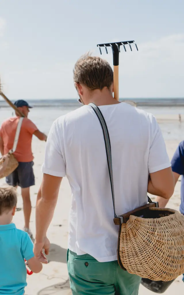 Une famille marchant sur la plage avec des outils pour chercher des coquillages
