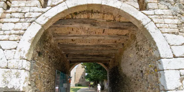 Passage voûté en pierre avec une fenêtre au-dessus et un panneau au sol