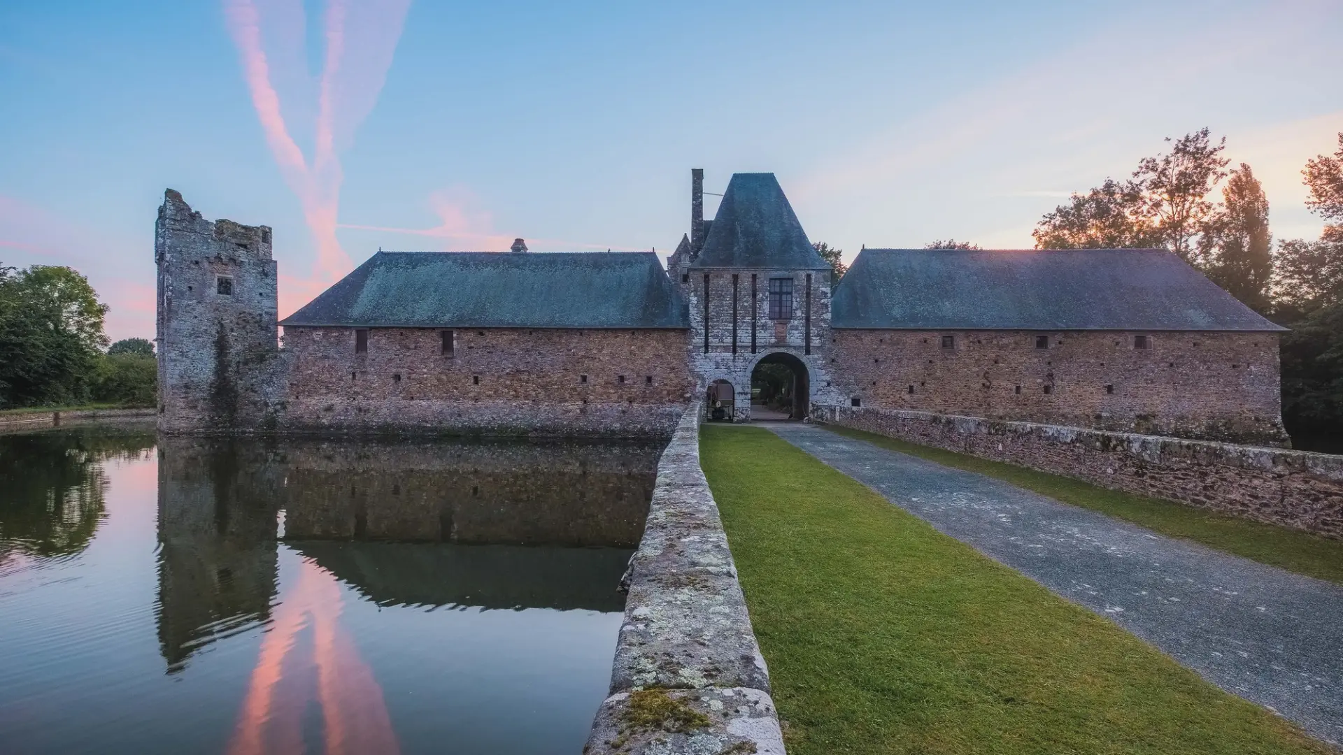 Medieval castle with moat and drawbridge at sunset