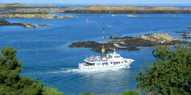 Bateau de croisière blanc naviguant près des rochers dans une mer bleue
