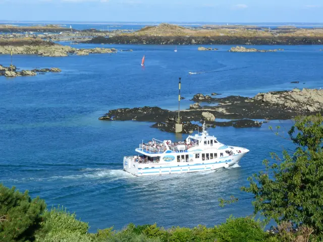 Bateau de croisière blanc naviguant près des rochers dans une mer bleue