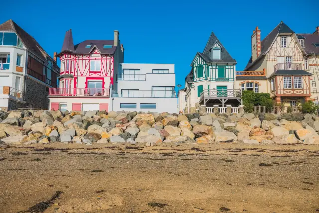 Colorful houses lined up on a beach with rocks in the foreground