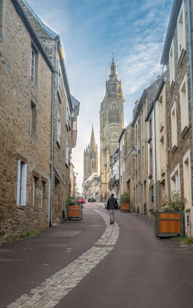 A cobblestone street leading to a cathedral with stone buildings on either side
