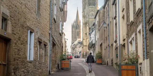 Une rue pavée menant à une cathédrale avec des bâtiments en pierre de chaque côté