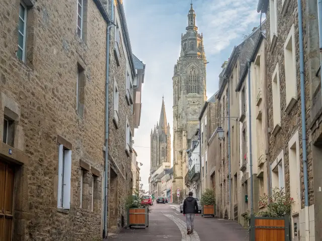 Une rue pavée menant à une cathédrale avec des bâtiments en pierre de chaque côté