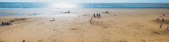 Escaliers menant à une plage de sable avec des gens se relaxant et jouant près de l'eau