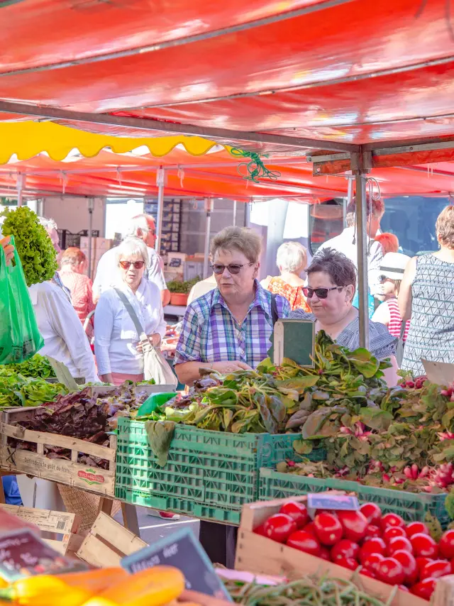 Menschen, die auf einem Markt unter roten und gelben Zelten einkaufen