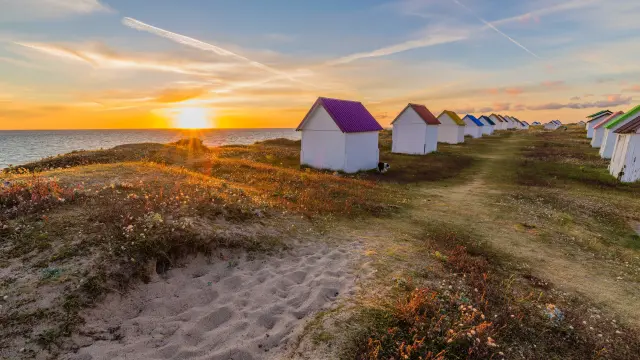 Alignement de cabanes de plage colorées au coucher du soleil