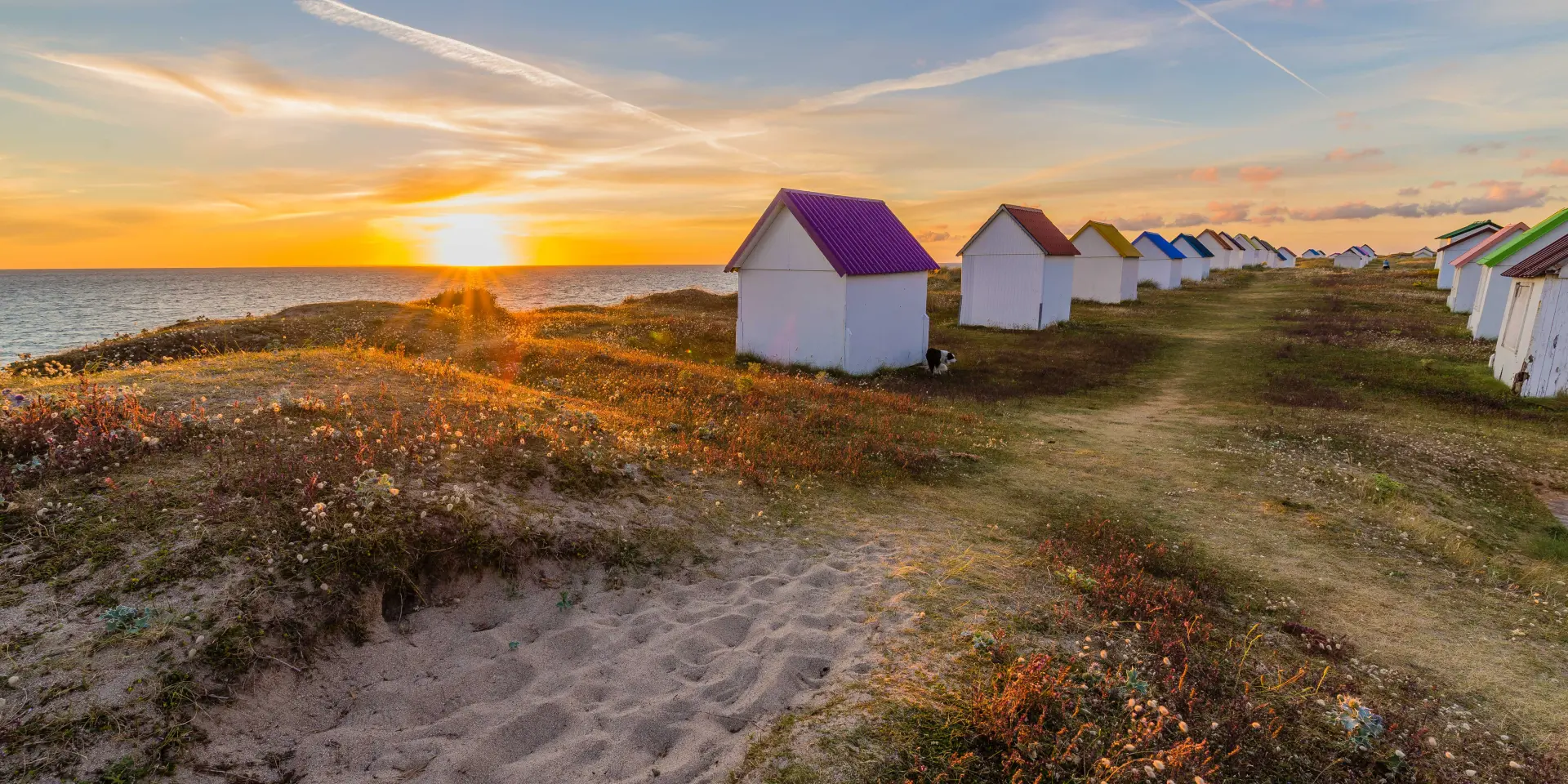 Row of colorful beach huts at sunset