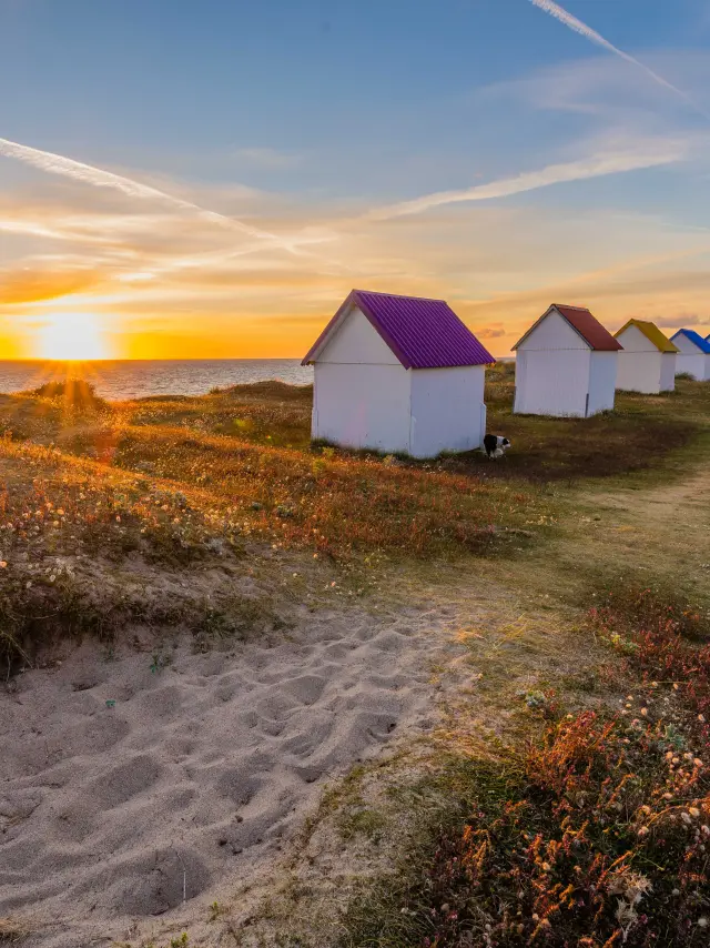 Alignement de cabanes de plage colorées au coucher du soleil