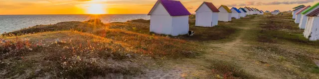 Alignement de cabanes de plage colorées au coucher du soleil