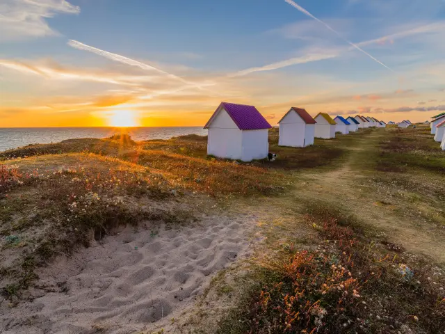Reihe bunter Strandhütten beim Sonnenuntergang