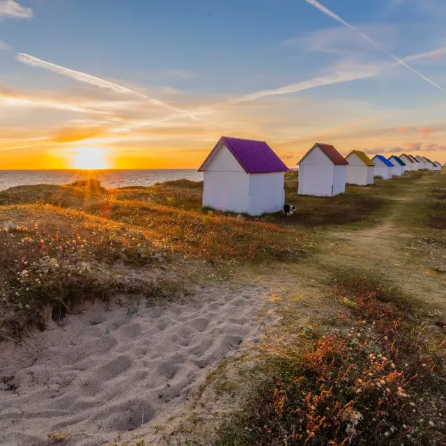 Row of colorful beach huts at sunset