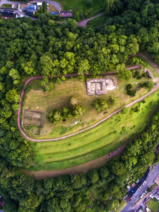 Vue aérienne d'une colline boisée avec des sentiers et des structures en pierre
