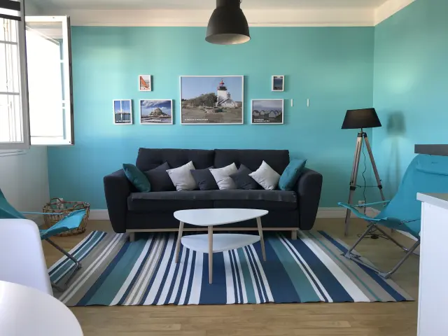 Wohnzimmer mit schwarzem Sofa, weißem Couchtisch und türkisfarbenen Wänden