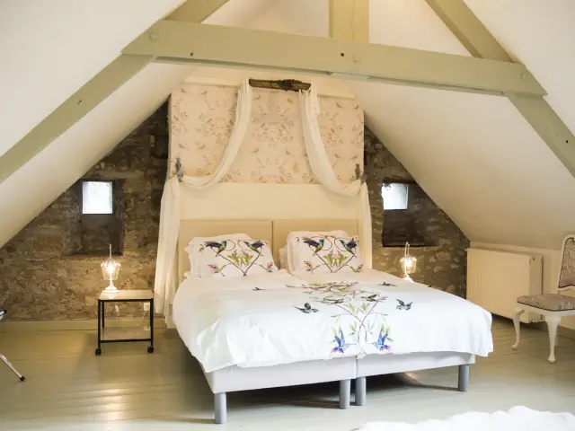 Schlafzimmer mit einem großen Himmelbett und freiliegenden Steinwänden