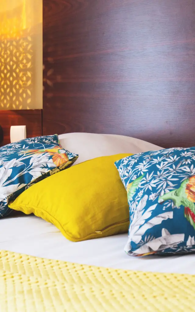 Bed with colorful pillows and a bedside lamp