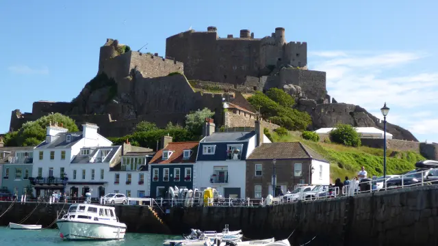 Château en pierre sur une colline au-dessus d'un port avec des bateaux amarrés