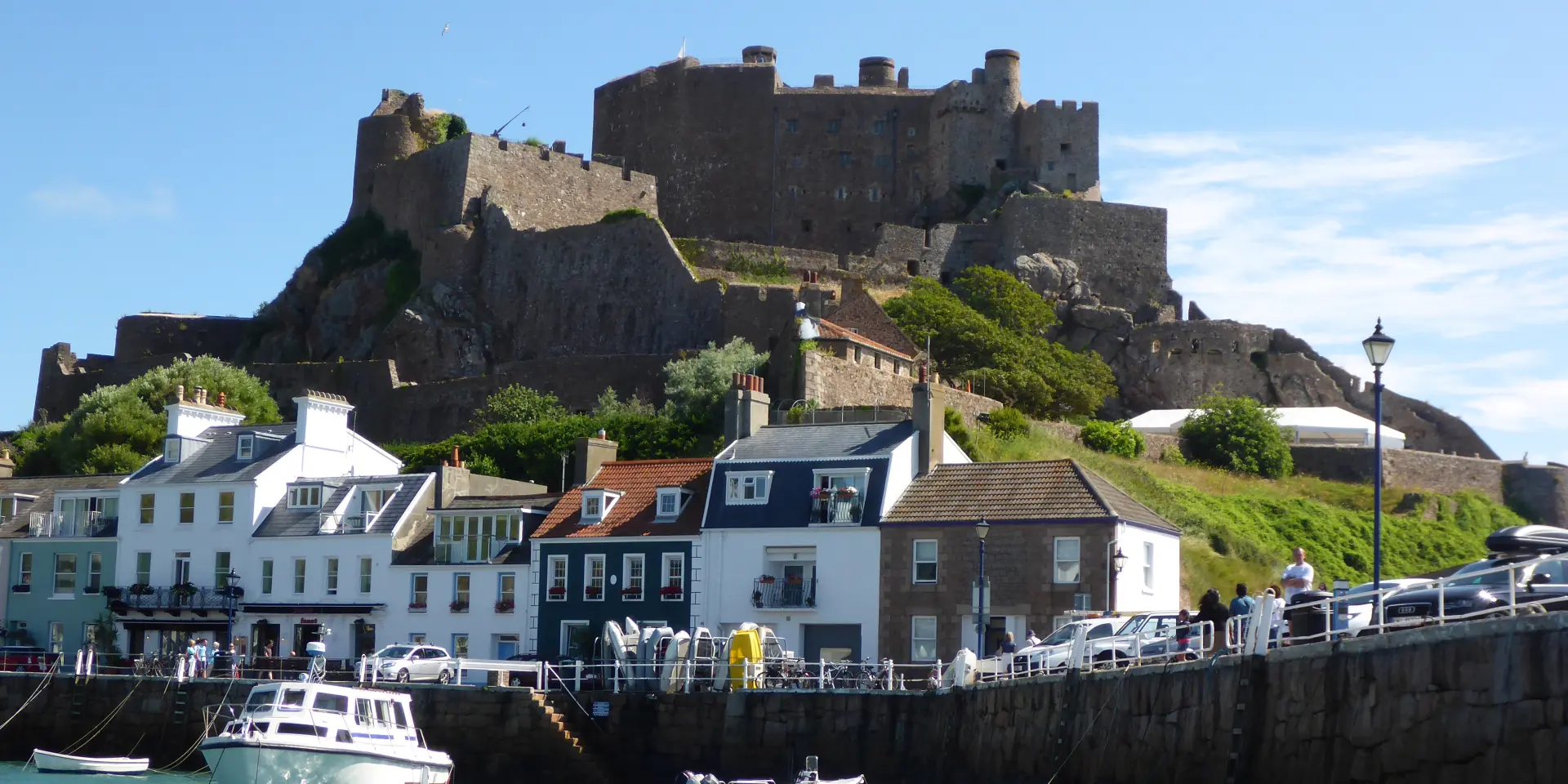 Stone castle on a hill above a harbor with moored boats