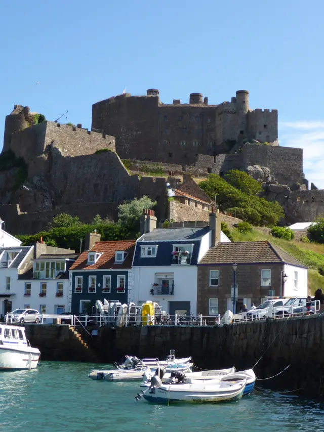 Château en pierre sur une colline au-dessus d'un port avec des bateaux amarrés