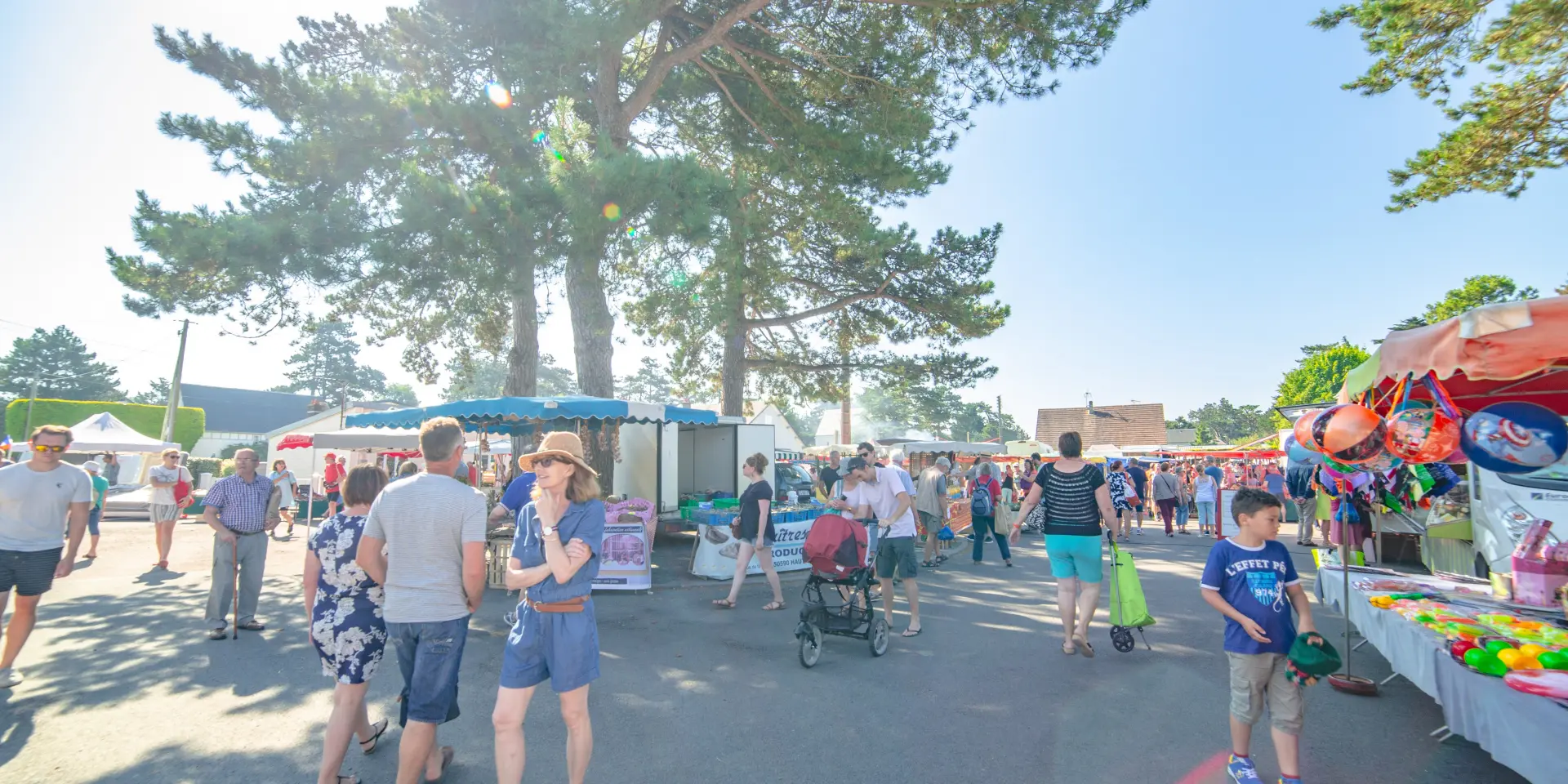 A lively crowd at an outdoor market under a clear sky