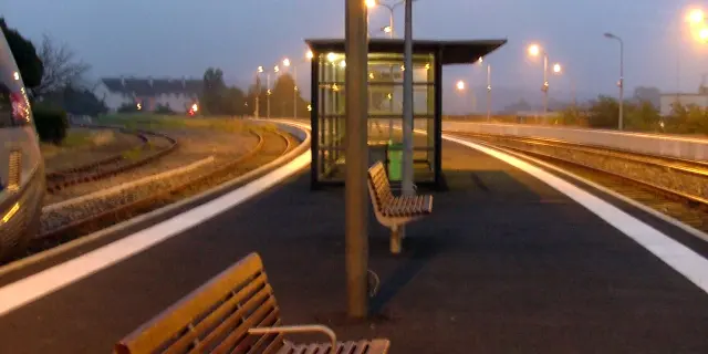 Leerer Bahnhof mit Bänken und einer beleuchteten Anzeigetafel