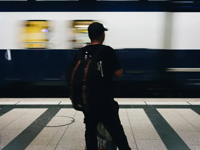Ein Mann mit einem Rucksack und einer Gitarre geht durch einen Bahnhof