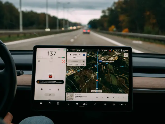 GPS-Tablet mit Straßenkarte und zwei Wasserflaschen auf dem Armaturenbrett