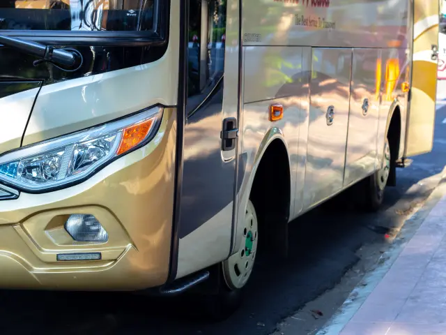 Bus de ville beige et jaune stationné le long d'un trottoir