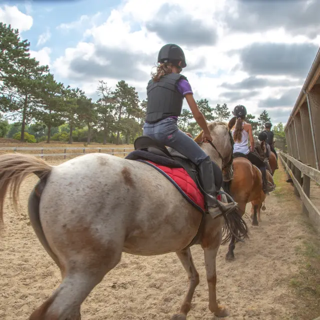 A person riding a horse in an outdoor arena
