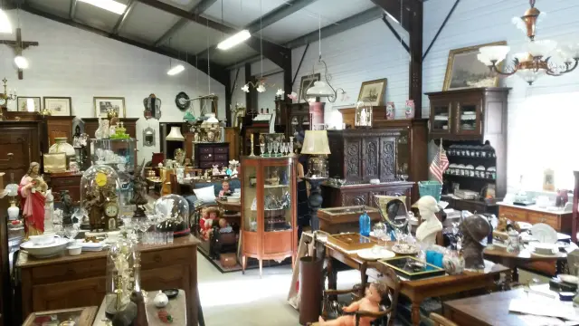 Un magasin d'antiquités rempli de meubles anciens, de lampes et d'objets décoratifs.