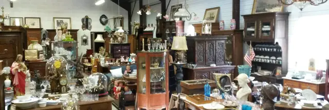 Un magasin d'antiquités rempli de meubles anciens, de lampes et d'objets décoratifs.