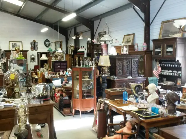 Un magasin d'antiquités rempli de meubles anciens, de lampes et d'objets décoratifs.