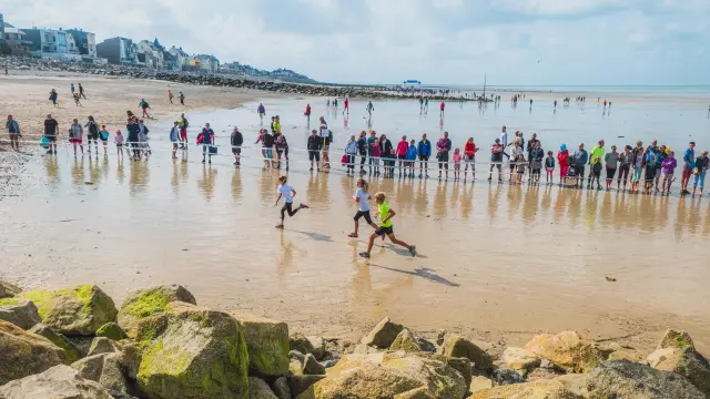 Participants courant sur une plage avec des spectateurs