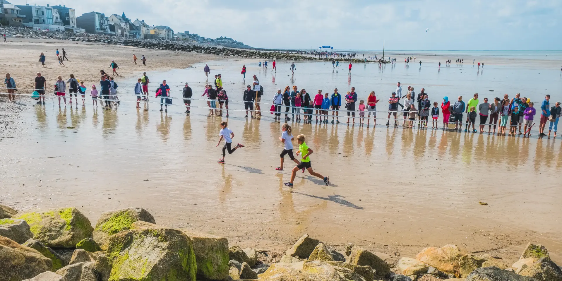 Participants courant sur une plage avec des spectateurs