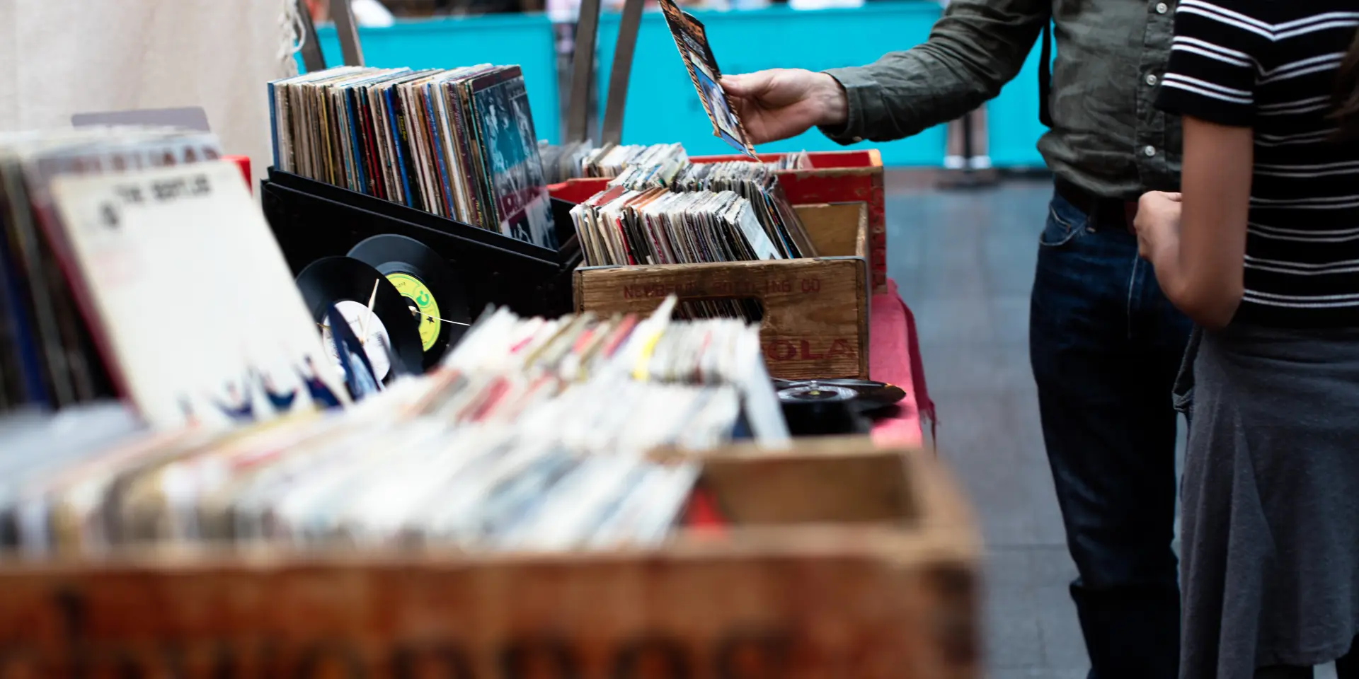 Person browsing through vinyl records at a vintage record market