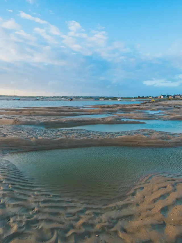 Marée basse sur une plage avec des flaques d'eau et des traces de pas