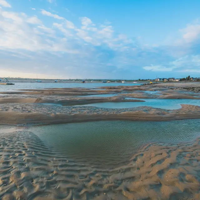 Low tide on a beach with water pools and footprints
