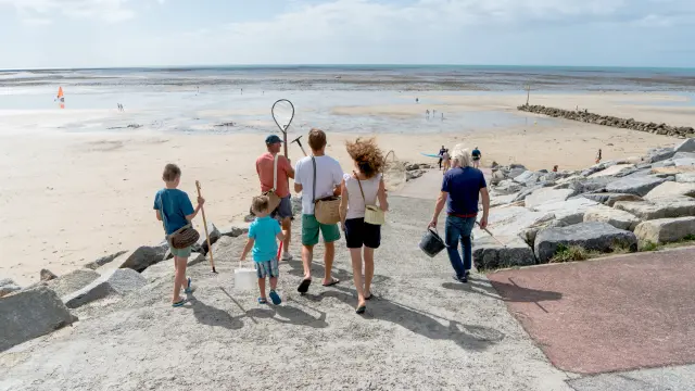 Eine Familie geht am Strand spazieren, mit Kindern, die Schmetterlingsnetze halten