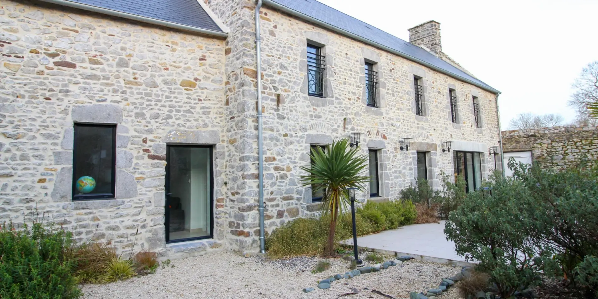 Stone house with large windows and landscaped garden