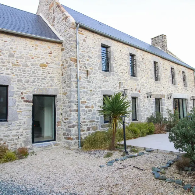 Stone house with large windows and landscaped garden