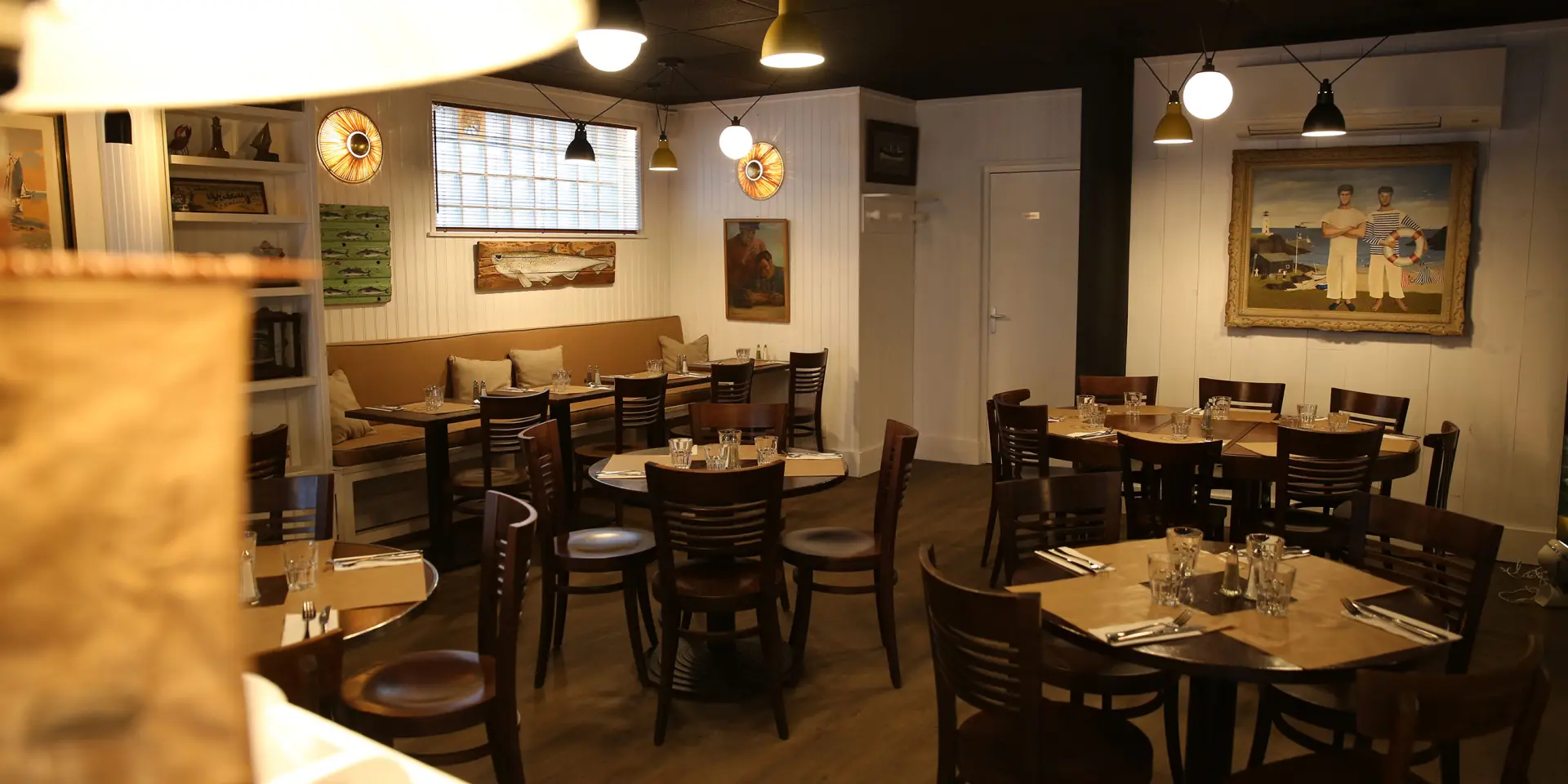 Innenraum eines Restaurants mit runden Tischen und Holzbänken