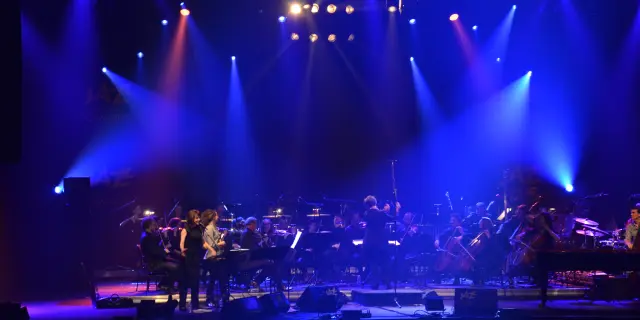 Orchestre symphonique jouant sur scène avec des lumières bleues