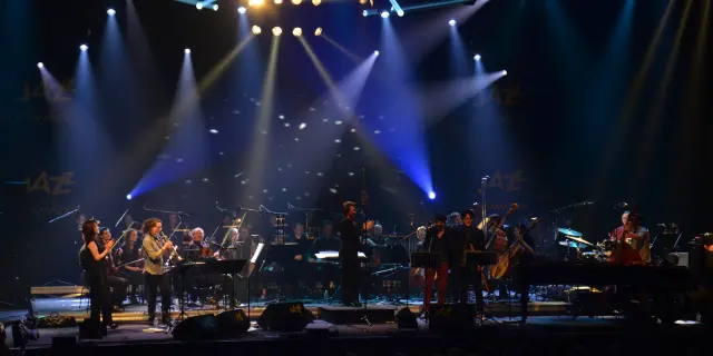 Orchestra playing on stage with bright spotlights