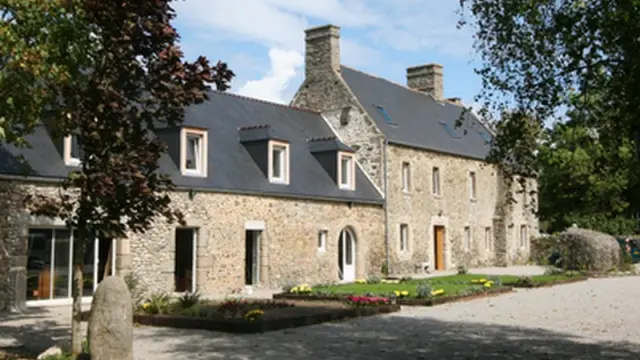 Maison en pierre avec toit en ardoise et jardin fleuri