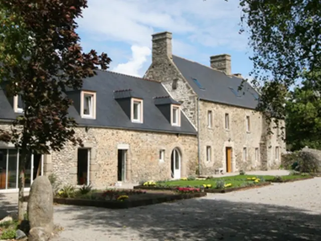 Maison en pierre avec toit en ardoise et jardin fleuri