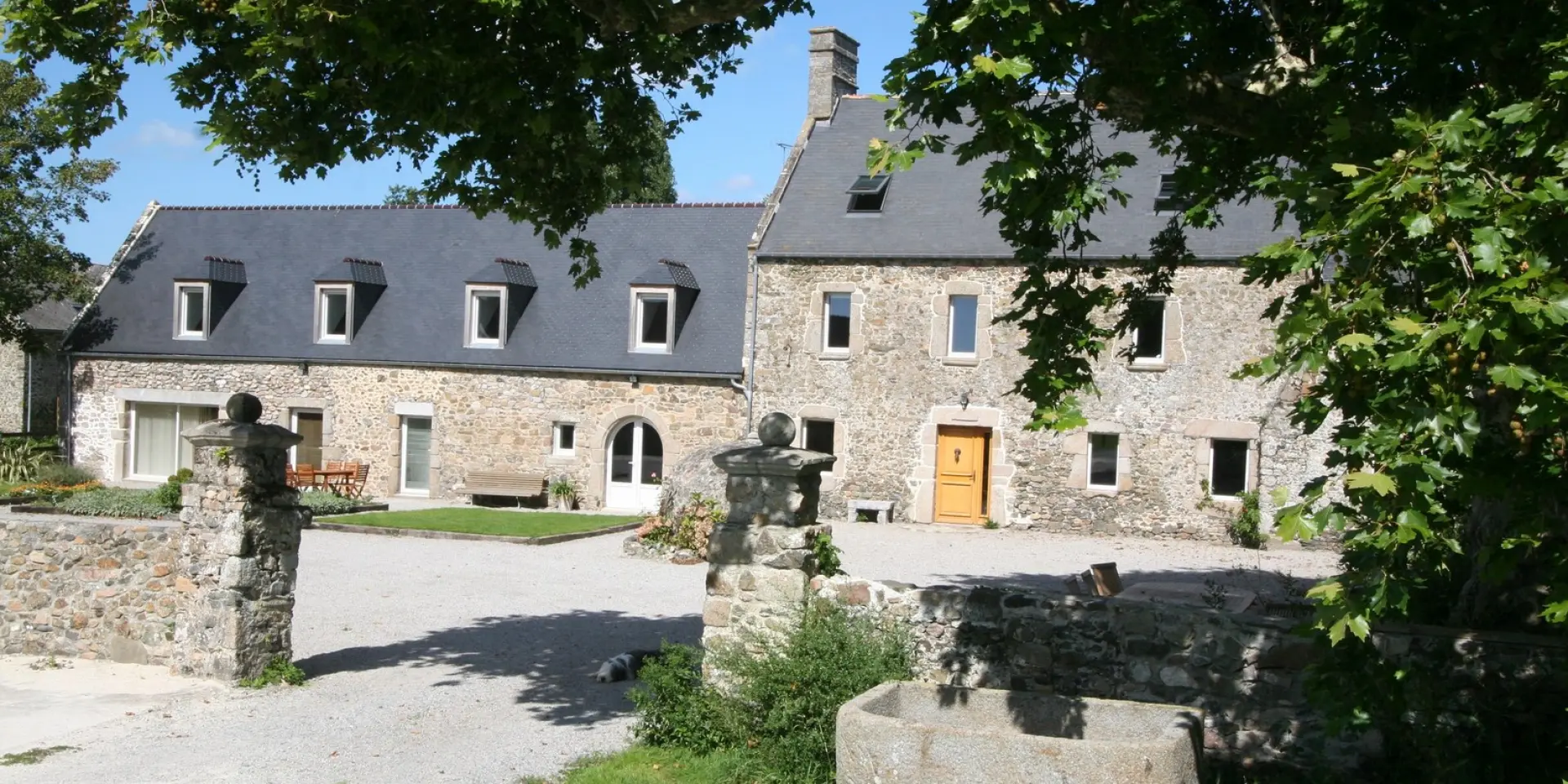 Grande maison en pierre avec un jardin et une fontaine