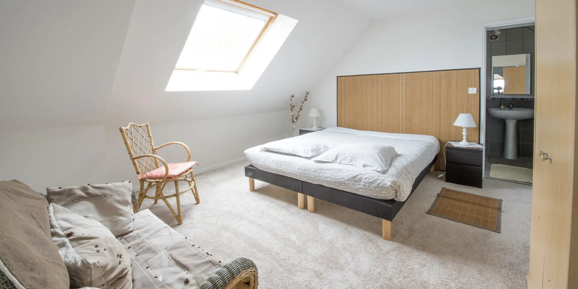 Chambre avec lit, fauteuil, et fenêtre de toit