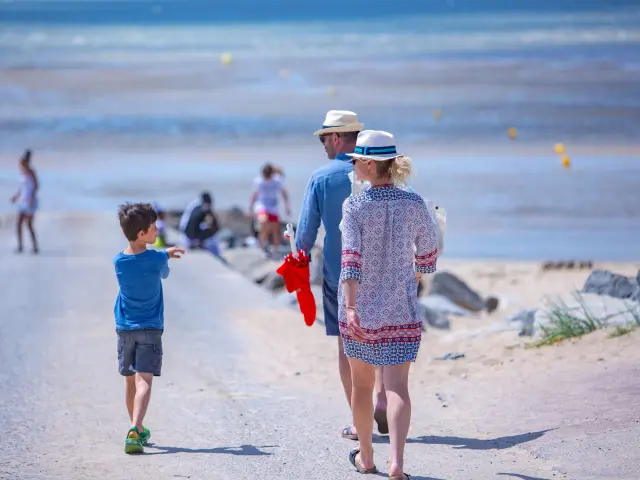 Une famille marche sur un chemin de plage
